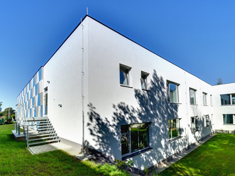 Photo: Exterior view, new building with light-coloured facade, stairs on the left and garden in the foreground