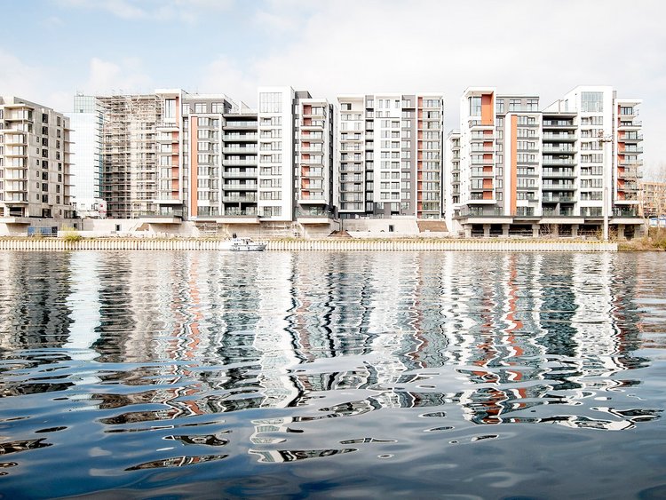 Photo: three completed buildings in the foreground; other buildings under construction; view from the river