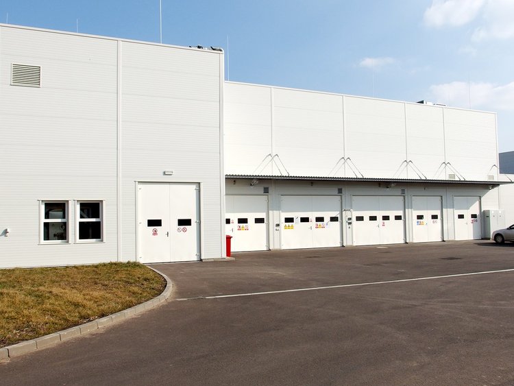 Photo: building with numerous access doors for loading lorries; tarmac surface in the foreground